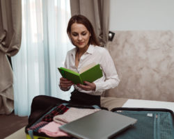 A businesswoman packing and preparing for a trip with a carry-on suitcase.
