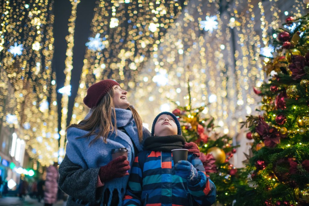 A mom and son enjoying an outdoor christams lights display. 