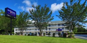 A three level building with a white exterior, trees surrounding, and a blue InTown Suites sign on the lawn.