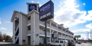 A InTown Suites sign with "low weekly rates" in white font at the bottom and an exterior of a building behind.