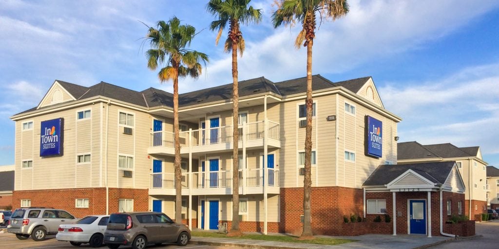 Exterior of a beige InTown Suites building with blue doors and two InTown Suites signs.