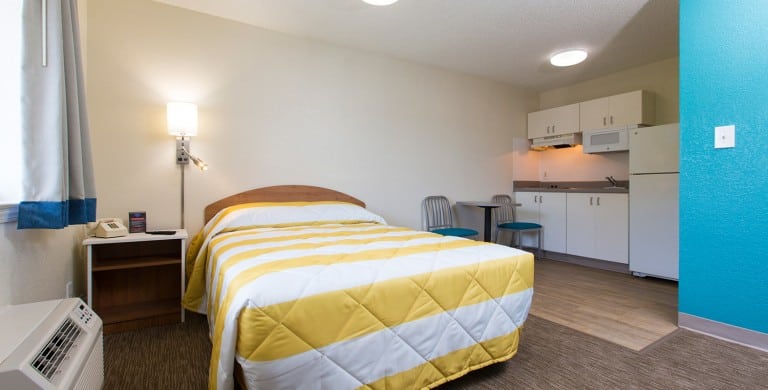 The interior of an InTown Suites studio with a queen size bed and kitchenette.