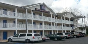 A white building with cars parked in front and an InTown Suites sign on the top.