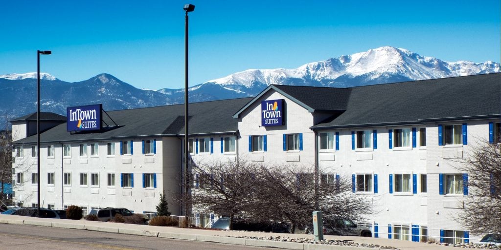 InTown Suites in Colorado Springs with tall, snow covered mountains in the background.