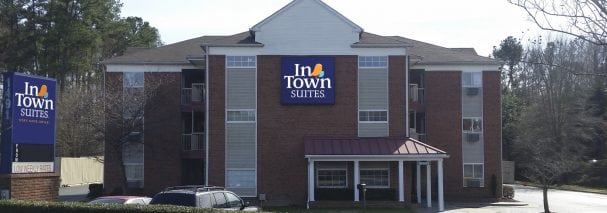 Un edificio de ladrillo y beige con un gran letrero azul InTown Suites en el centro.