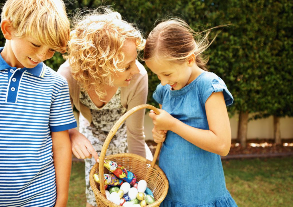 a mom and two kids enjoying a fun easter egg hunt 