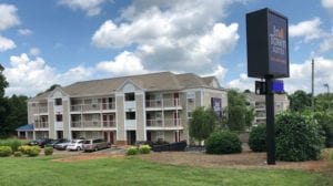 Beige building with shrubs and an "InTown Suites" sign in front of the property.