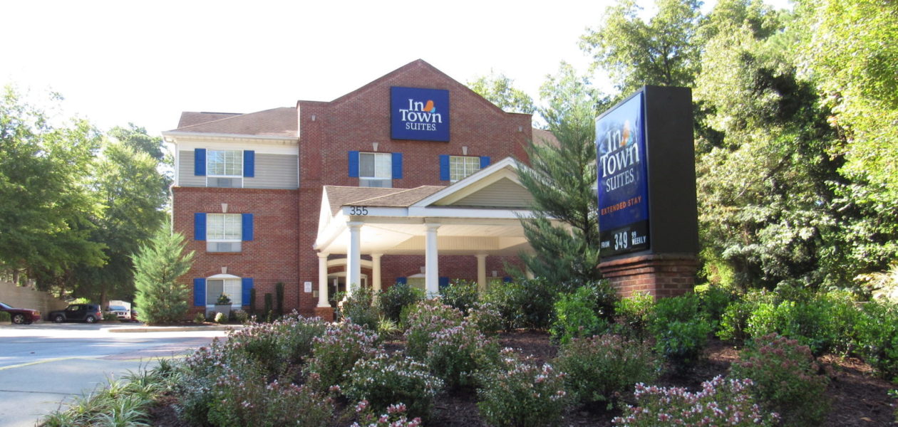 A brick building with shrubs and plants at the front of the property