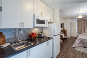 Modern kitchen with microwave, two-burner stove top, and full-size refrigerator.