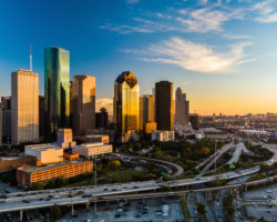 An image of the Houston skyline with a beautiful sky and sunrise in the distance.