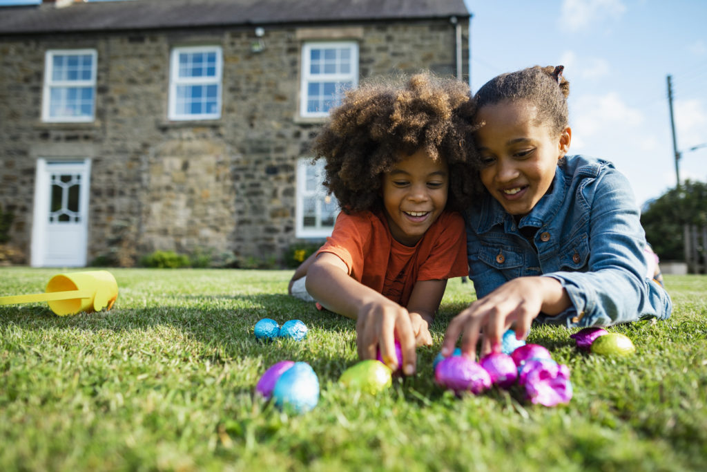 A brother and sister counting eggs from their Easter egg hunt, one fun way to celebrate Easter safely.