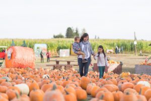 A woman and her two kids exploring a pumpkin patch, one of the many fall activities in Houston. 