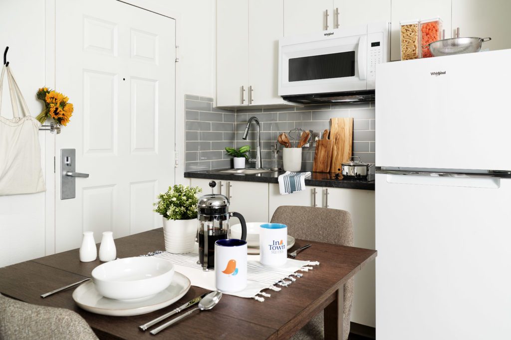 In-room kitchen with full-size refrigerator, two burner stove top, microwave, cabinets, and drop leaf table and chairs.