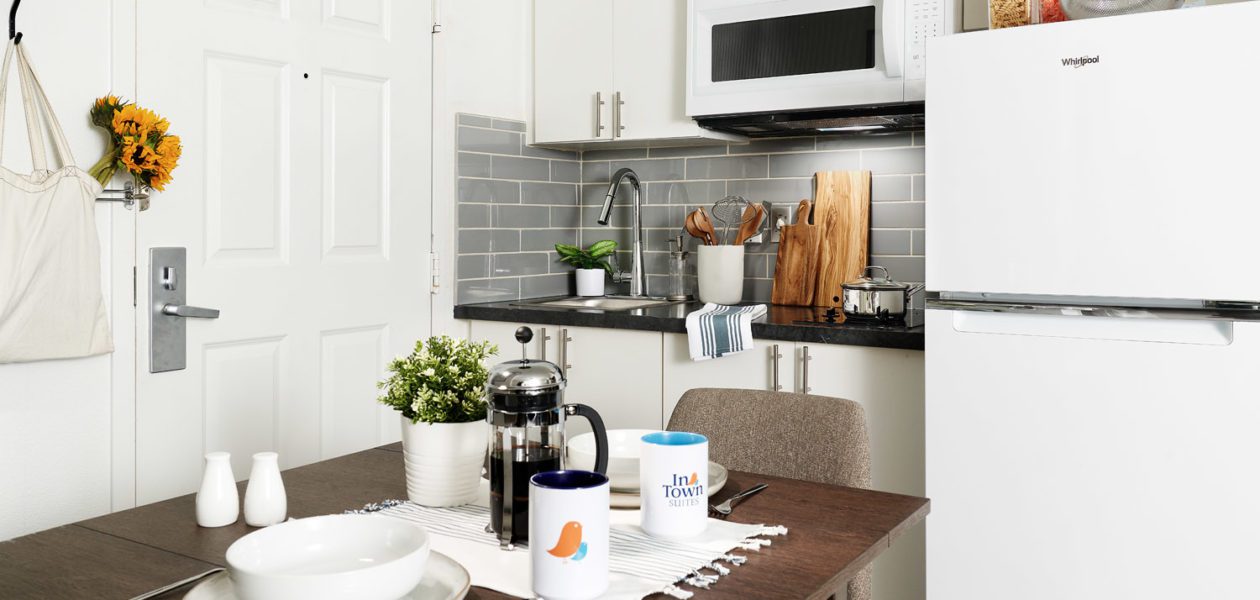 In-room kitchen with full-size refrigerator, two burner stove top, microwave, cabinets, and drop leaf table and chairs.