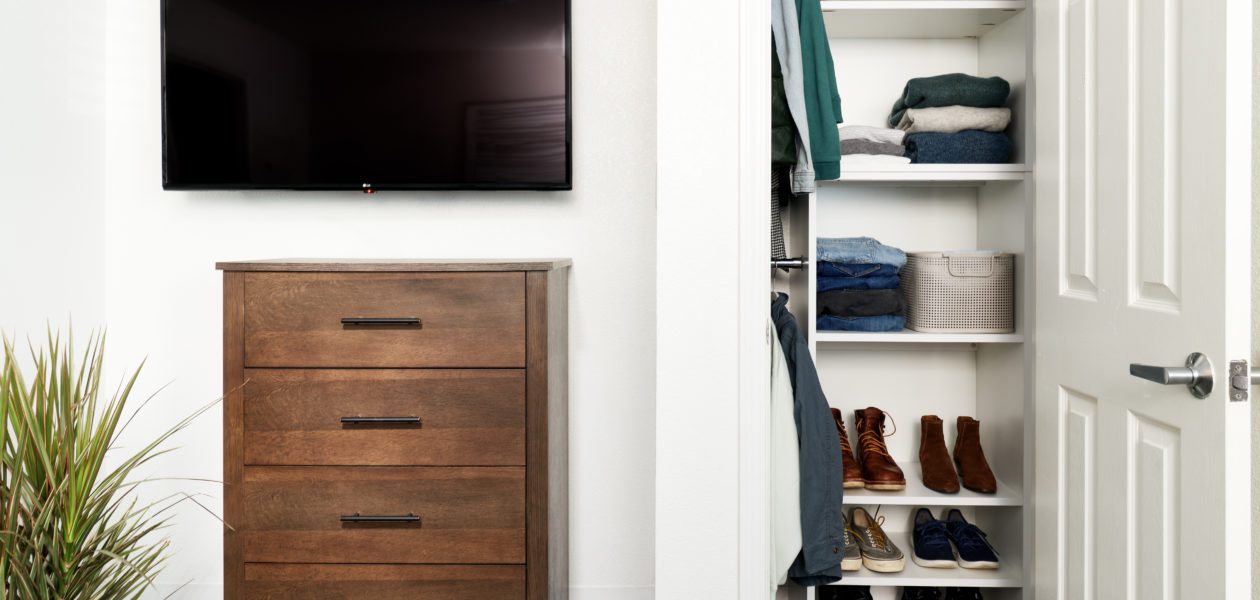 Picture of large HDTV with dresser and closet.