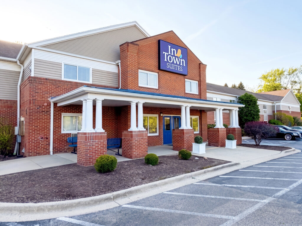 InTown Suites hotel exterior with brick facade, white columns, and blue entrance doors